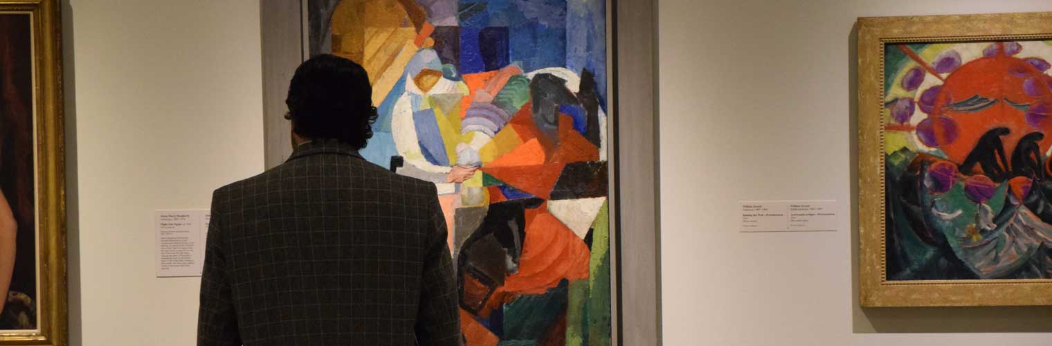a back of a man looking at colorful abstract paintings