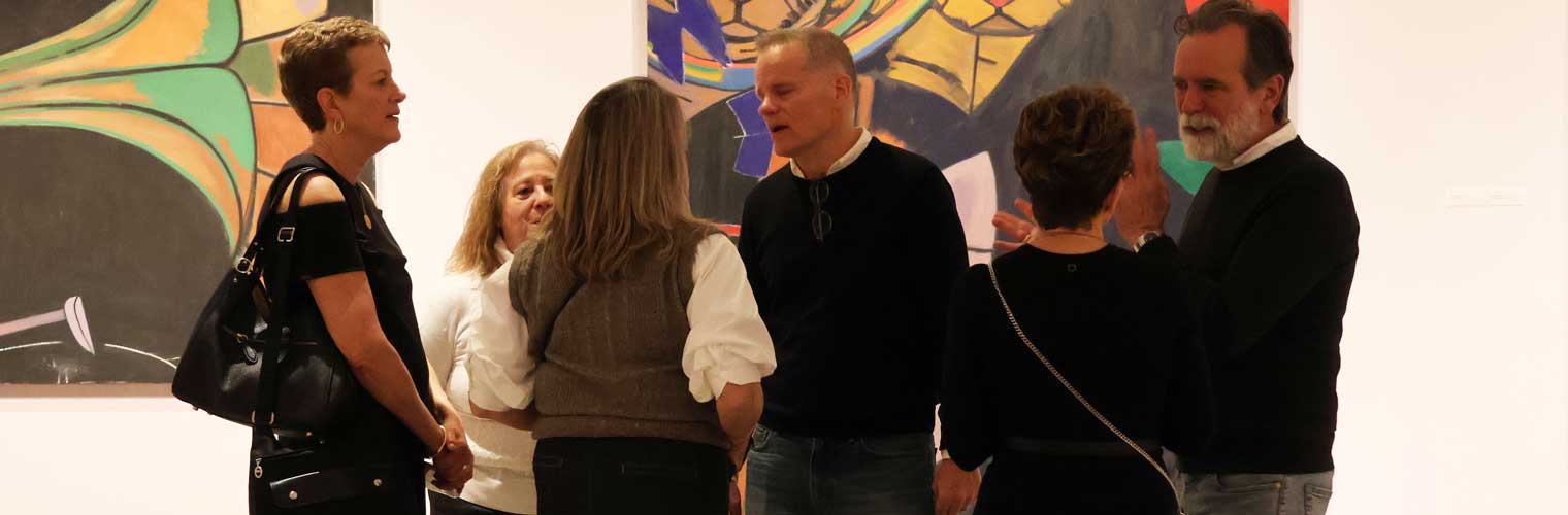 a group of people socializing by modern art, colorful paintings