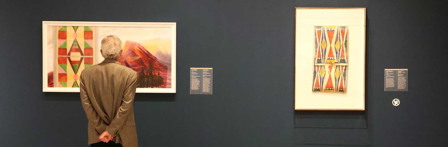 back of an older man in a suit looking at a modern art, abstract painting