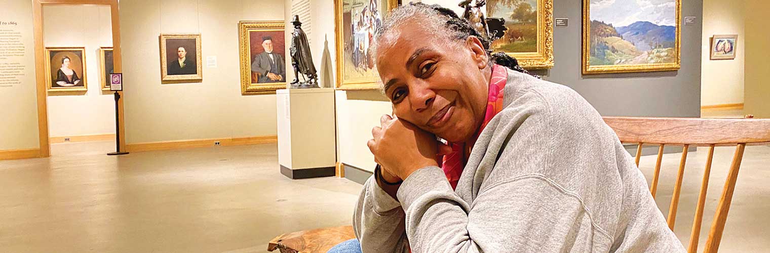woman visitor sitting on the gallery bench smiling at the camera