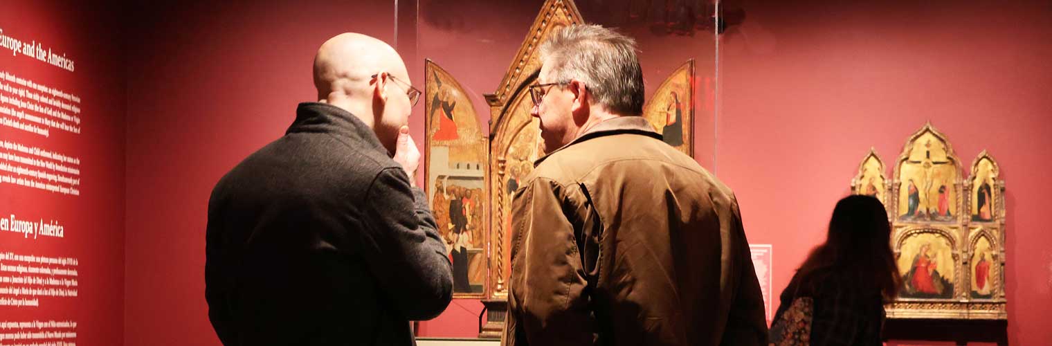 two men discussing art in a gallery with painted red walls