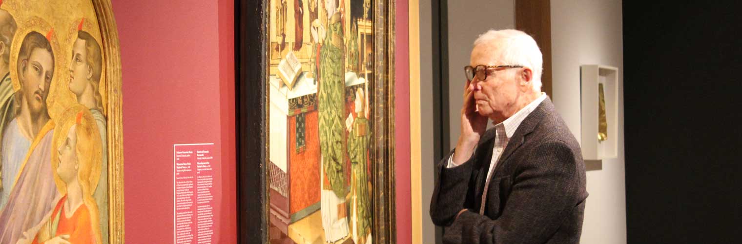 older man looking at paintings 