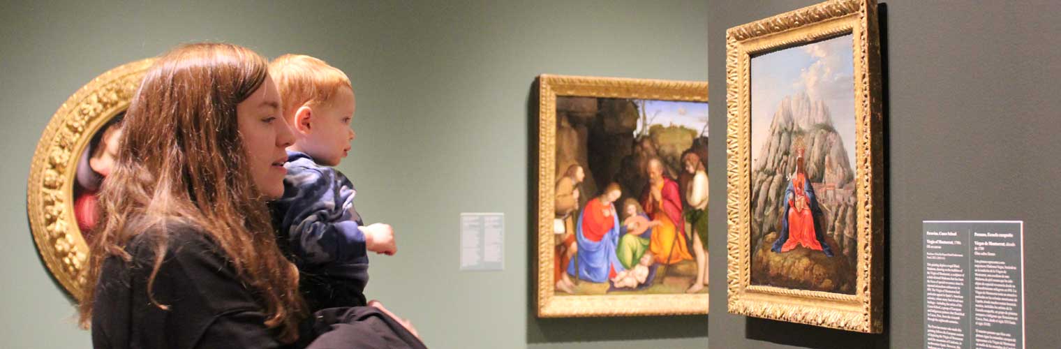 Young mother with her baby looking at paintings 