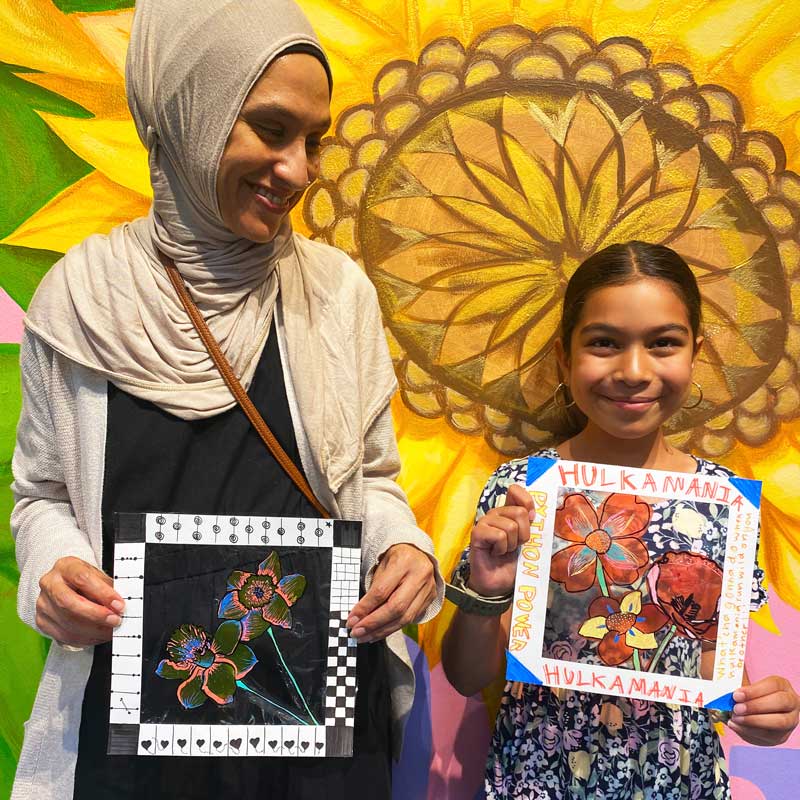 mother and daughter holding up art pieces they created